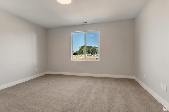 spare room with baseboards, visible vents, and light colored carpet