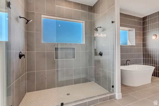 full bathroom with a shower stall, tile walls, tile patterned flooring, and a freestanding tub