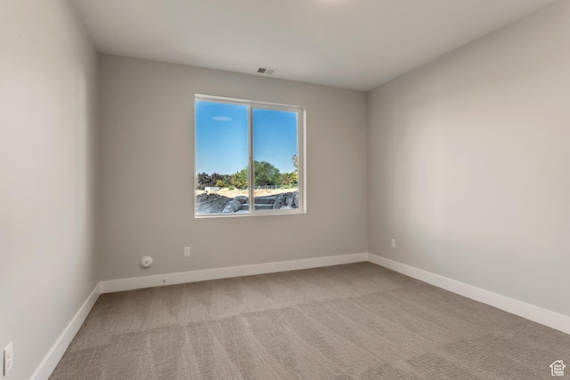 carpeted spare room featuring baseboards and visible vents