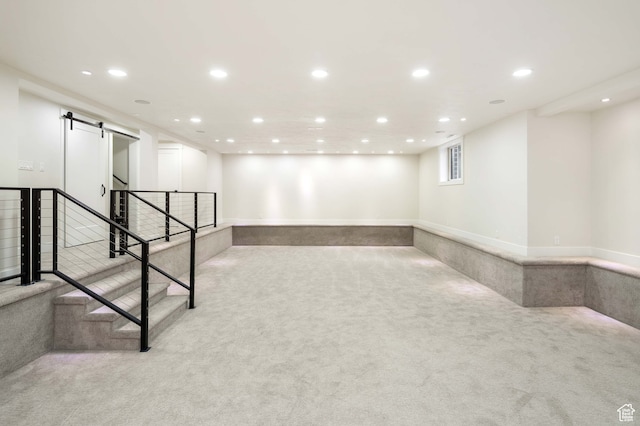 basement featuring a barn door and light carpet