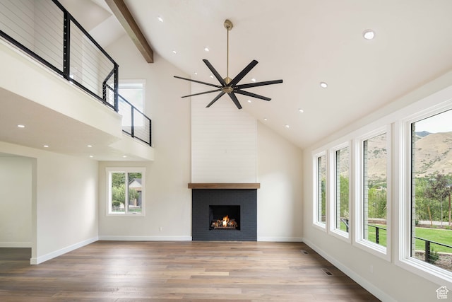 unfurnished living room featuring ceiling fan, plenty of natural light, high vaulted ceiling, and a large fireplace