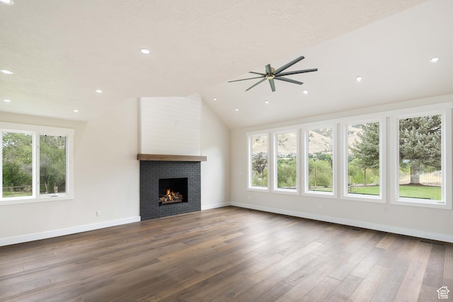 unfurnished living room with ceiling fan, lofted ceiling, a textured ceiling, a tile fireplace, and hardwood / wood-style floors