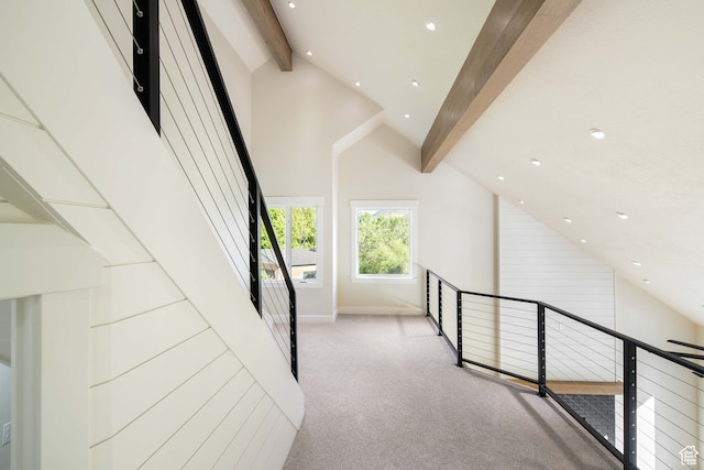 interior space with light colored carpet, beam ceiling, and high vaulted ceiling