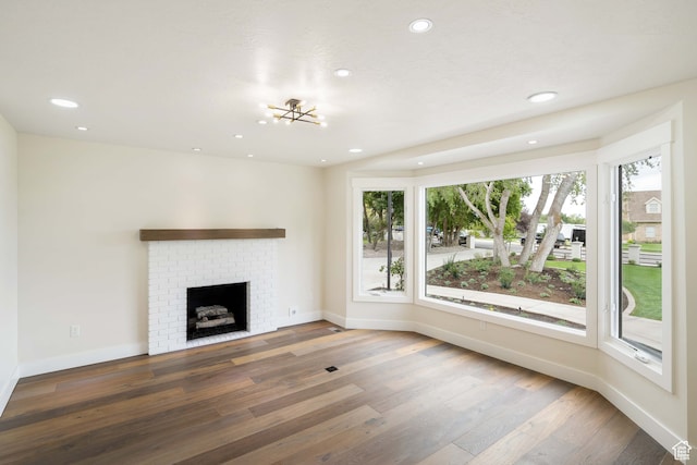 unfurnished living room with dark hardwood / wood-style floors, a brick fireplace, and a wealth of natural light