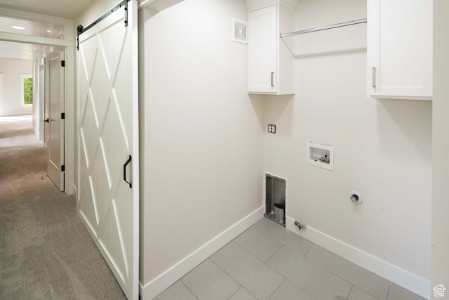 laundry room featuring cabinets, electric dryer hookup, a barn door, light tile patterned floors, and hookup for a washing machine