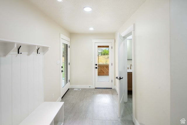 mudroom with a textured ceiling, light hardwood / wood-style floors, and sink