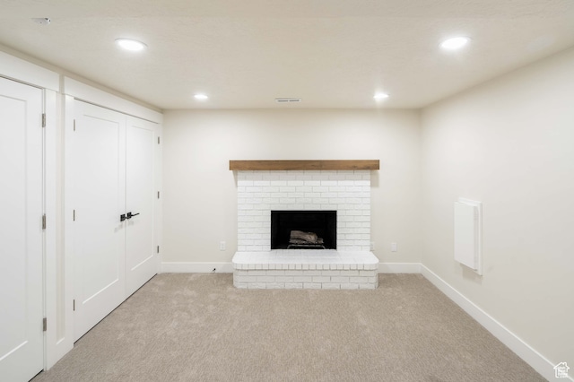 unfurnished living room with a brick fireplace and light colored carpet