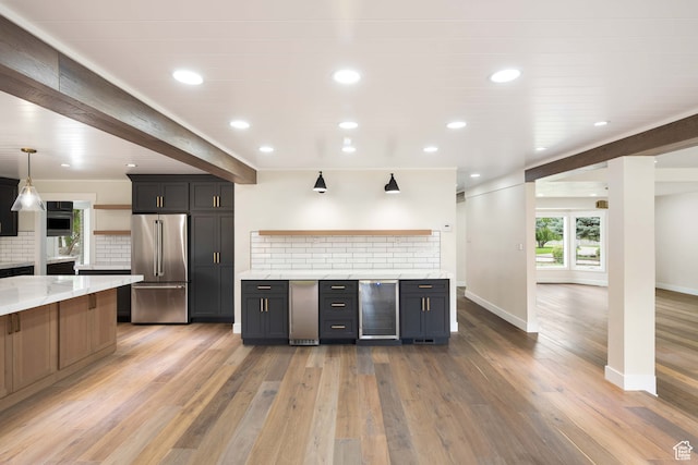kitchen with pendant lighting, wine cooler, high end fridge, backsplash, and light hardwood / wood-style floors