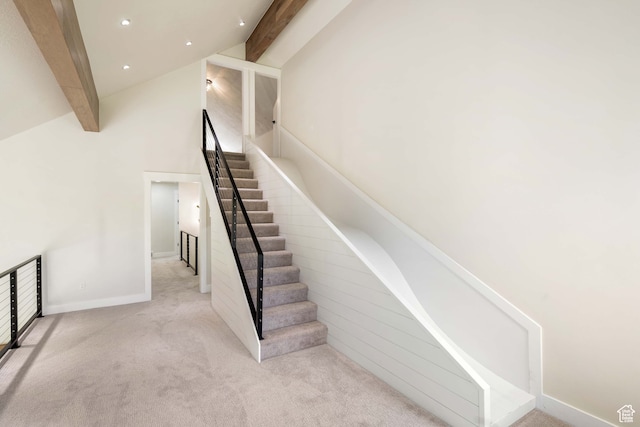 stairs with high vaulted ceiling, beamed ceiling, and carpet flooring