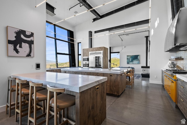 27 Normans Way, Park City, UT 84060 - kitchen with a towering ceiling, a center island, built in fridge, baseboards, and a breakfast bar