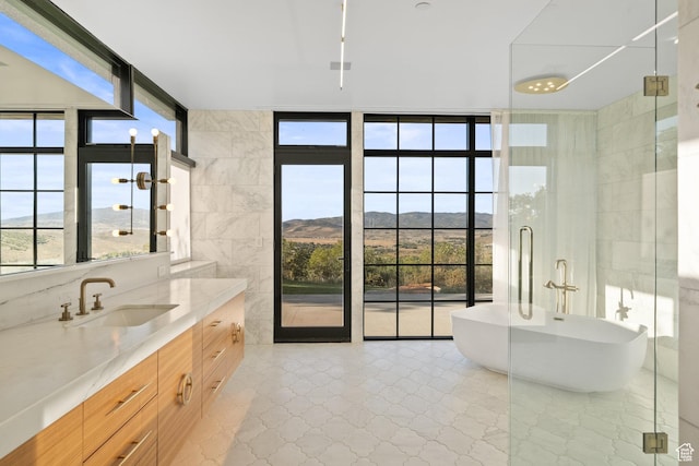 27 Normans Way, Park City, UT 84060 - bathroom featuring healthy amount of natural light, expansive windows, vanity, a soaking tub, and tile walls