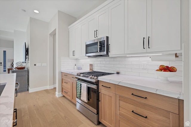 4755 S Purcell Dr, St George, UT 84790 - kitchen with baseboards, light stone countertops, stainless steel appliances, tasteful backsplash, and light wood-style floors