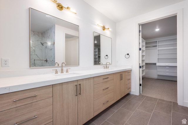 bathroom featuring a walk in closet, a sink, a marble finish shower, tile patterned flooring, and double vanity