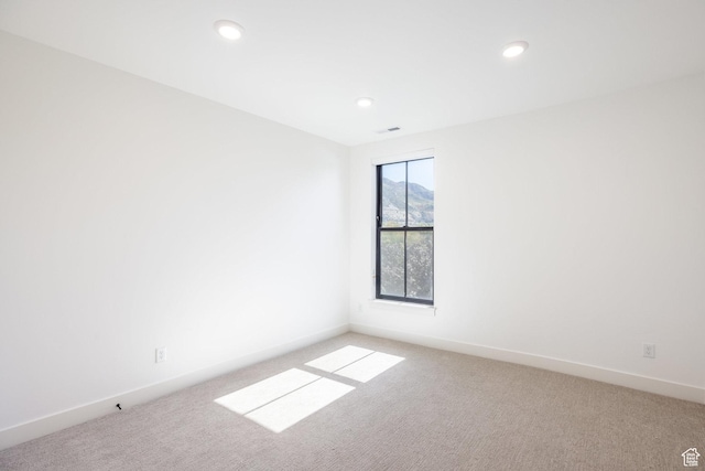 unfurnished room with visible vents, baseboards, and light carpet