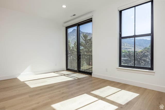 spare room with visible vents, wood finished floors, recessed lighting, a mountain view, and baseboards