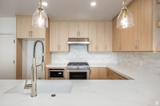 kitchen featuring light brown cabinetry, under cabinet range hood, a sink, backsplash, and gas stove