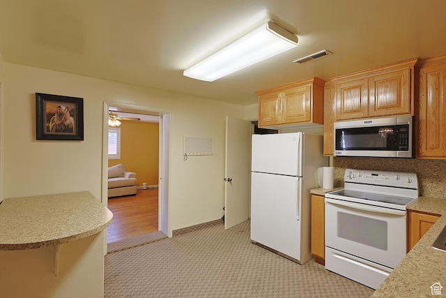 kitchen featuring white appliances, light countertops, light colored carpet, and ceiling fan