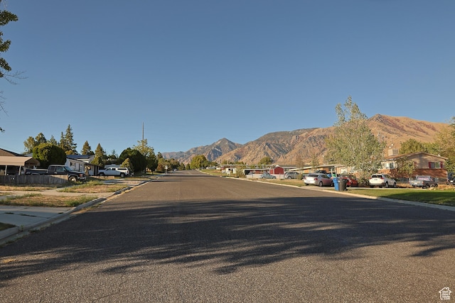 view of asphalt street with a mountain view, a residential view, and curbs