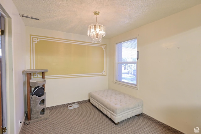 carpeted bedroom featuring a textured ceiling and a chandelier