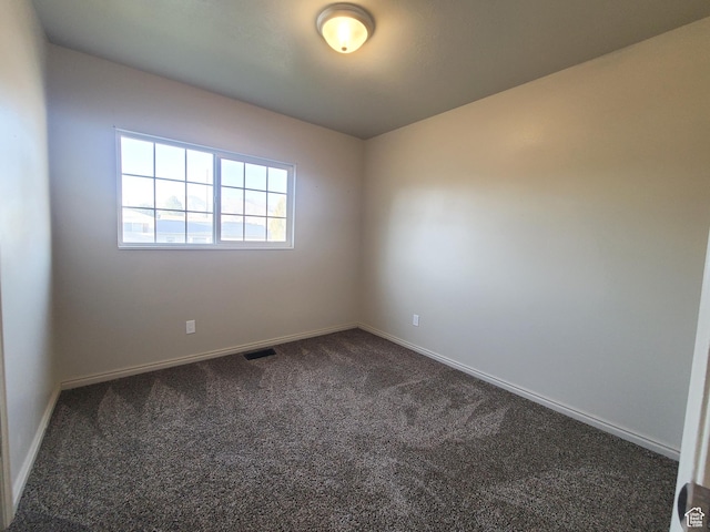 unfurnished room with dark carpet, baseboards, and visible vents
