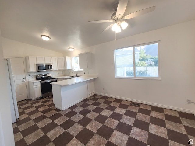 kitchen featuring a peninsula, a sink, dark floors, light countertops, and appliances with stainless steel finishes