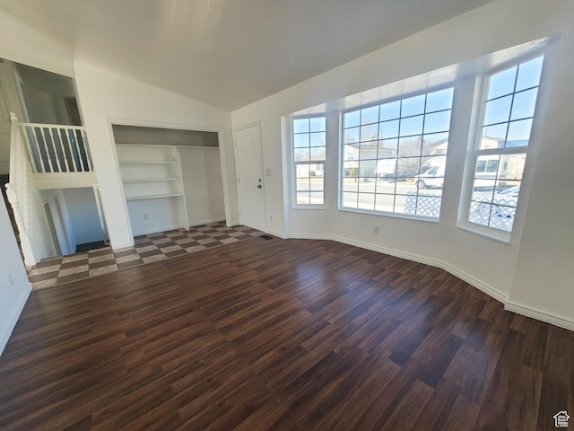 unfurnished living room with dark wood finished floors, built in shelves, and a healthy amount of sunlight