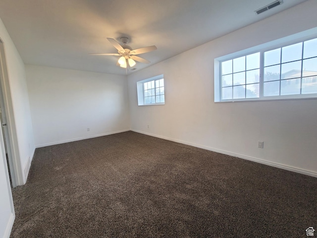 unfurnished room featuring dark carpet, ceiling fan, baseboards, and visible vents