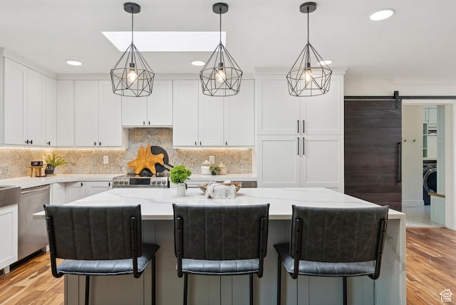 3041 Homestead Rd, Park City, UT 84098 - kitchen featuring stainless steel appliances, white cabinets, a barn door, washer / dryer, and recessed lighting