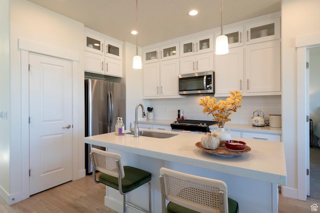 kitchen featuring tasteful backsplash, white cabinets, a sink, stainless steel appliances, and hanging light fixtures