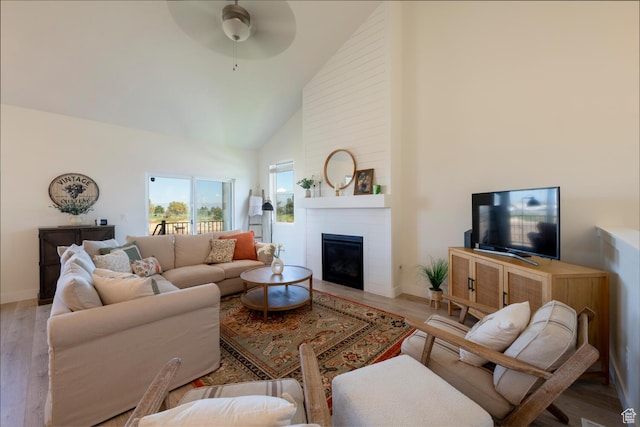living area featuring a fireplace, wood finished floors, ceiling fan, and high vaulted ceiling