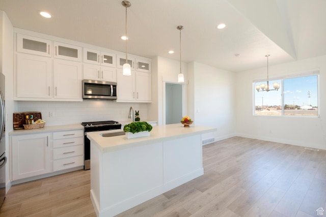 kitchen with stainless steel appliances, light countertops, backsplash, a sink, and white cabinetry