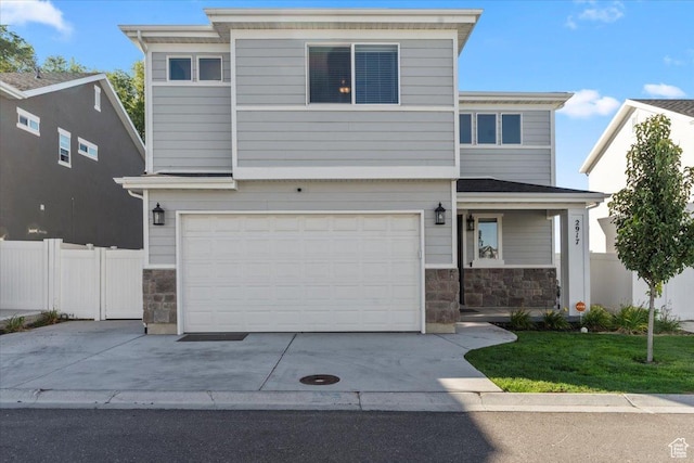 view of front facade with driveway, fence, stone siding, and a garage
