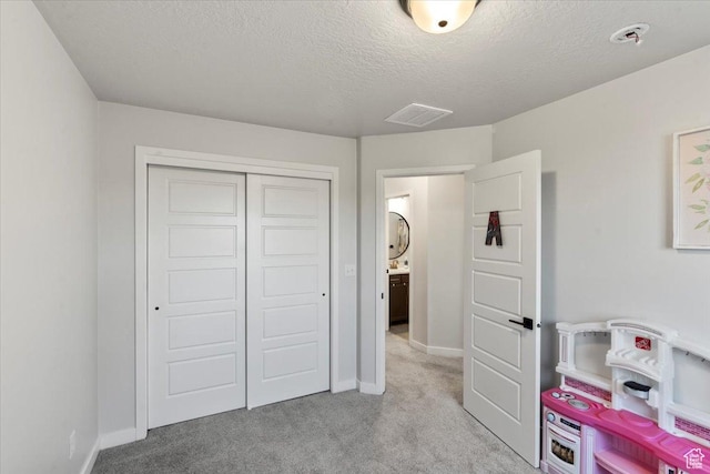playroom with a textured ceiling, light colored carpet, baseboards, and visible vents