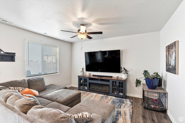 living area featuring visible vents, ceiling fan, wood finished floors, and a textured ceiling
