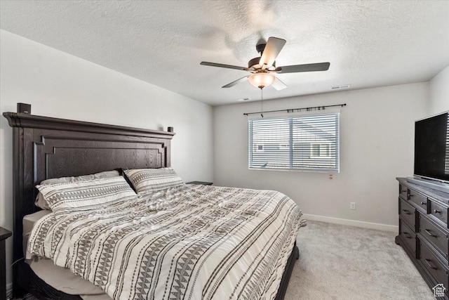 bedroom with ceiling fan, light colored carpet, baseboards, and a textured ceiling