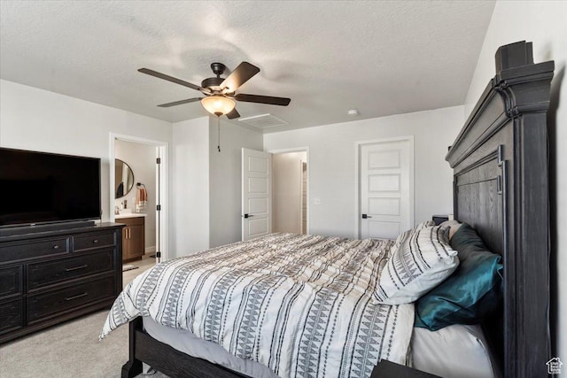 bedroom featuring light carpet, ceiling fan, ensuite bath, and a textured ceiling