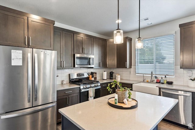 kitchen featuring a sink, light countertops, appliances with stainless steel finishes, dark brown cabinetry, and decorative backsplash