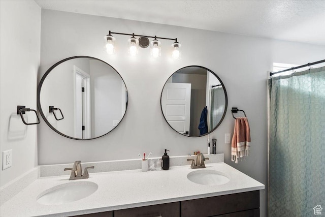 bathroom with a shower with shower curtain, double vanity, and a sink