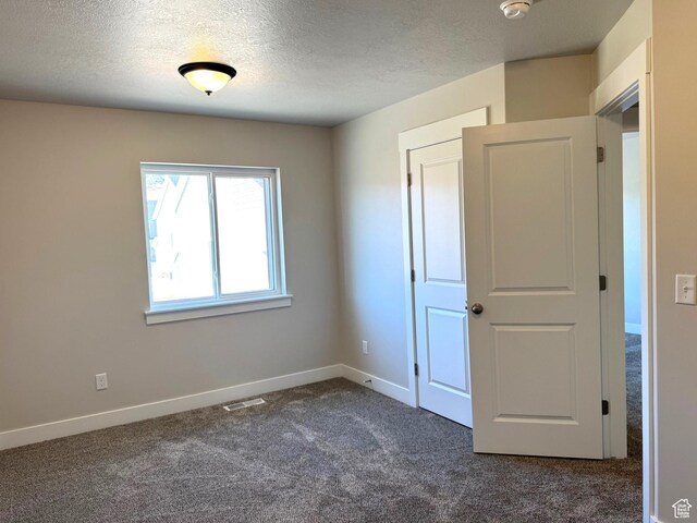 184 W Seasons Ln Unit 56, Garden City, UT 84028 - unfurnished bedroom featuring baseboards, visible vents, dark carpet, and a textured ceiling