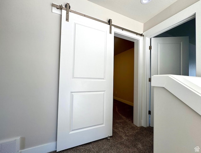 184 W Seasons Ln Unit 56, Garden City, UT 84028 - corridor with dark carpet, a barn door, visible vents, and baseboards