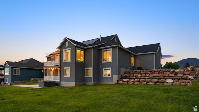 209 N Elk Ridge Dr, Elk Ridge, UT 84651 - back of house at dusk featuring a balcony, a hot tub, and a lawn