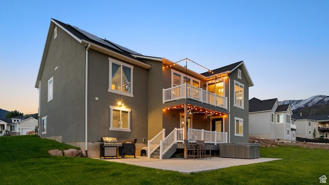 209 N Elk Ridge Dr, Elk Ridge, UT 84651 - back of property at dusk featuring a balcony, a patio, a lawn, and stucco siding