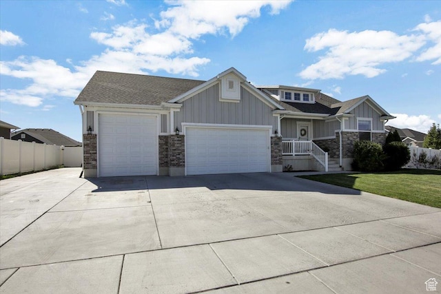 craftsman house with board and batten siding, an attached garage, concrete driveway, and fence