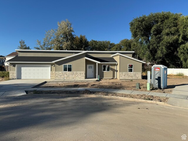 view of front of property featuring concrete driveway, an attached garage, and stone siding