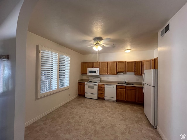 502 S 1040 E Unit 221, American Fork, UT 84003 - kitchen with a sink, brown cabinetry, white appliances, arched walkways, and baseboards