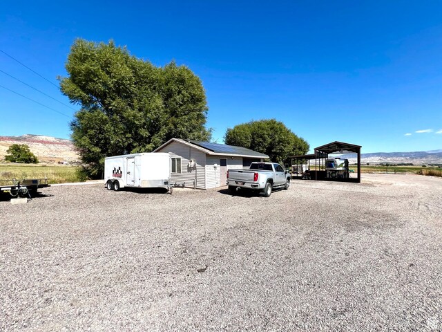 1942 N Sevier Valley Canal Rd, Richfield, UT 84701 - view of front of house featuring a detached carport, a mountain view, solar panels, and driveway