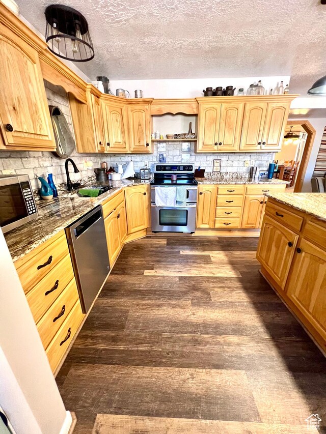 1942 N Sevier Valley Canal Rd, Richfield, UT 84701 - kitchen featuring tasteful backsplash, dark wood-style flooring, light stone counters, appliances with stainless steel finishes, and a sink