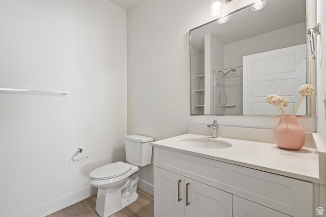 bathroom featuring walk in shower, vanity, toilet, baseboards, and wood finished floors