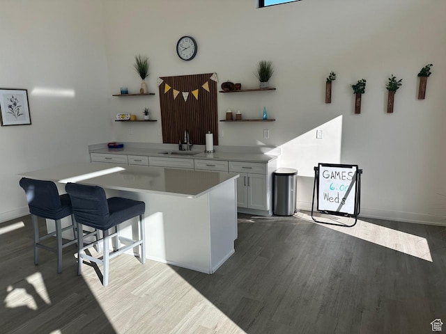 kitchen featuring a sink, baseboards, open shelves, and dark wood finished floors
