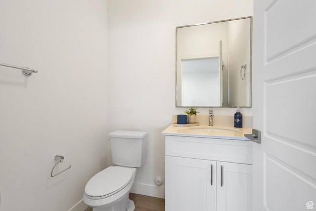 half bath with vanity, baseboards, and toilet